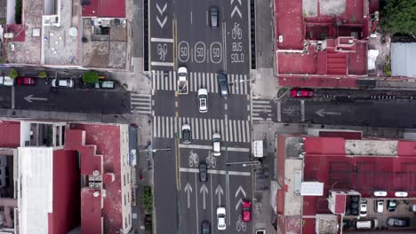 Flight-directly-above-car-traffic-traveling-on-Felix-Cuevas-street-in-downtown-Mexico-city-center,-with-walkway,-crosswalk,-directional-white-arrows,-bicycle-sign-and-lines,-overhead-aerial-tracking