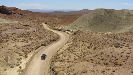 Black-SUV-4x4-speeds-down-a-dry-dirt-road-in-the-desert-leaving-behind-a-dust-trail