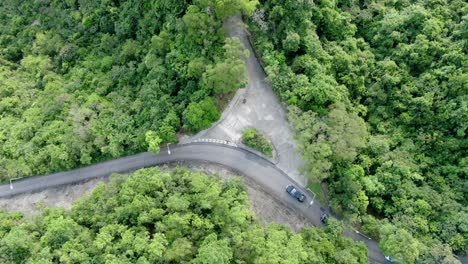 Aerial-view-of-a-narrow-winding-mountain-road-surrounded-by-lush-green-nature