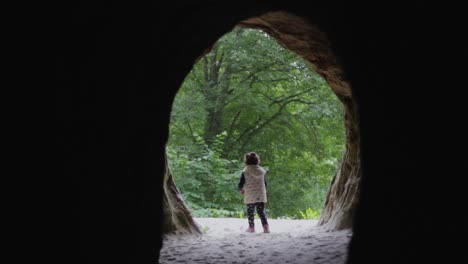 Lost-child-little-girl-walking-out-of-a-cave-entrance
