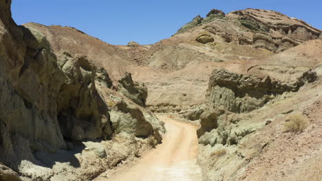 Viajando-Lentamente-Por-Un-Camino-De-Tierra-Curvo-Que-Se-Corta-Entre-Dos-Grandes-Formaciones-Rocosas-En-El-Desierto-De-Mojave