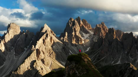Man-stands-at-Dolomites,-long-shot-Aerial-pan,-Italy