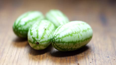 Raw-fresh-tiny-green-Mexican-cucamelon-on-wooden-kitchen-surface-selective-focus-left-dolly-closeup