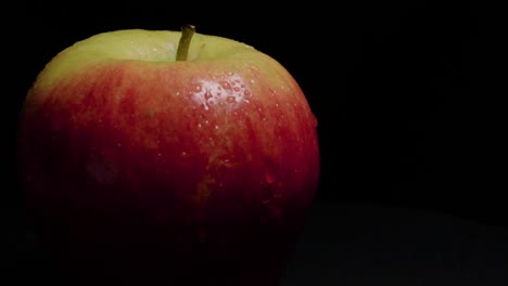 Fuji-Apple-Rotating-Off-center-on-Black-Background-with-Copy-Space,-Closeup