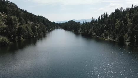 Drone-advancing-through-a-big-lake-and-descending-to-approach-to-the-water,-in-La-Cerdanya,-Catalunya