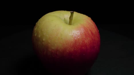 Tilt-Up-of-Dewy-Red-and-Yellow-Apple-Isolated-on-Black-Background,-Closeup