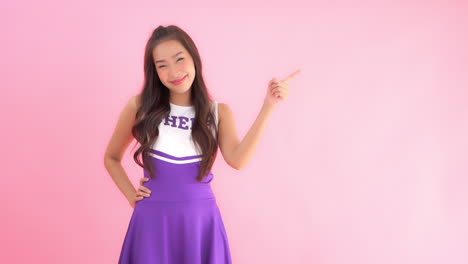 Porträt-Einer-Glücklichen-Asiatischen-Teenie-Cheerleaderin,-Die-Mit-Dem-Finger-Auf-Etwas-Zeigt