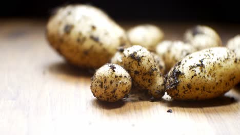 Patatas-Orgánicas-De-Cosecha-Propia-Enfoque-Poco-Profundo-Cubierto-De-Tierra-En-La-Superficie-De-La-Cocina-De-Madera