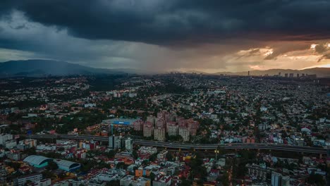 Aerial-drone-lapse-view-of-dark-clouds-moving-over-a-highway-and-the-cityscape,-during-sunset,-in-Mexico-city,-America---Reverse,-tracking,-hyperlapse-shot