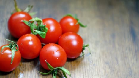 Tomates-Cherry-Mojados-Jugosos-Rojos-Diminutos-Frescos-Crudos-En-El-Enfoque-Selectivo-De-La-Superficie-De-La-Cocina-De-Madera
