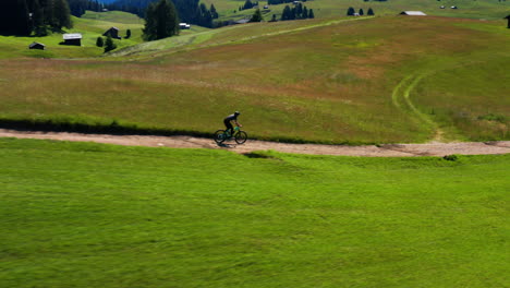 Man-on-bike-traveling-through-Alpe-di-Siusi-Dolomite-plateau-in-Italy
