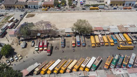 aerial,-drone-timelapse-shot-of-buses-heading-out-of-a-parking-lot-in-Guatemala,-4k