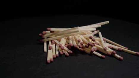 Pile-of-matches-rotating-on-black-background,-Closeup