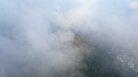 High-altitude-early-morning-fog-over-Hong-Kong-Lion-rock-mountain-ridge,-Aerial-view