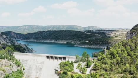 Nach-Unten-Kippbare-Luftaufnahme-Eines-Massiven-Staudamms-Mit-Straße-Darauf-In-Spanien