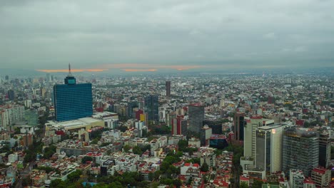 Aerial-moving-time-lapse-view-of-overcast-clouds-moving-over-the-city,-revealing-a-colorful-sunrise-sky,-in-Mexico,-America---Reverse,-hyperlapse,-drone-shot
