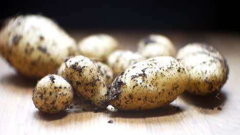 Bio-Kartoffeln-Aus-Eigenem-Anbau,-Flacher-Fokus,-Mit-Erde-Bedeckt,-Auf-Hölzerner-Küchenoberfläche,-Linker-Dolly