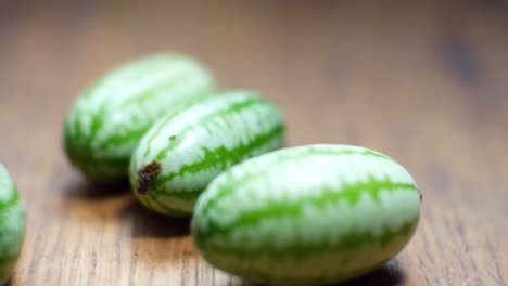 Raw-fresh-tiny-green-Mexican-cucamelon-placed-on-wooden-kitchen-surface-selective-focus-dolly-left