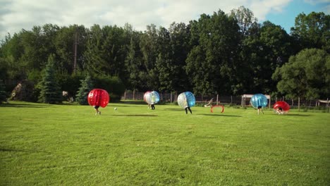 A-young-group-of-men-is-playing-Bubble-football-in-the-park,-one-of-them-scores-a-goal-after-the-pass-from-the-corner-kick