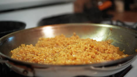 Couscous-simmering-and-sizzling-in-a-skillet-on-the-stove-with-steam-rising-in-slow-motion