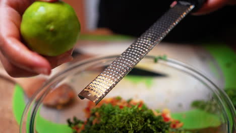 Zesting-a-lime-over-a-special-homemade-recipe-with-the-ingredients-in-a-bowl-with-a-microplane-grater