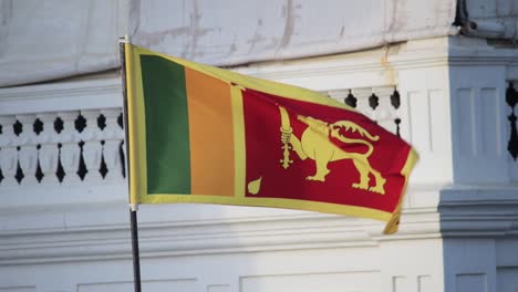 Sri-Lankan-National-Flag-waving-infront-of-the-Rampart-Hotel-and-Restaurant-in-Galle-Fort-Sunset-lighting-in-background,-Slow-Motion-static-b-roll-clip