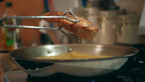 Grilled-chicken-breast-dripping-with-savory-juices-over-a-skillet-full-of-simmering-couscous---slow-motion
