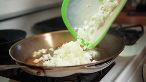 Pour-chopped-onions-into-a-hot-skillet-to-saute-with-oil-or-butter---slow-motion