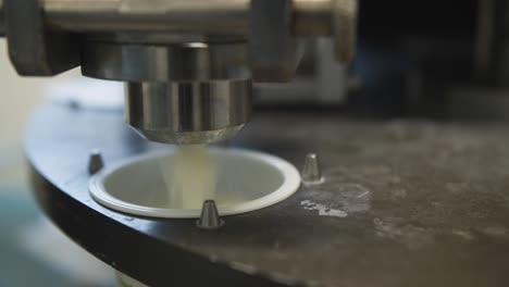 Closeup-on-rotating-automated-yogurt-production-line-pouring-into-pots