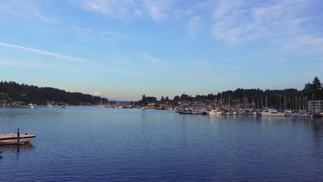 Sailboats-Moored-At-The-Docking-Terminal-Of-Gig-Harbor-Marina-And-Boatyard-In-Washington-With-Distant-View-Of-The-Snowy-Mount-Rainier-Peak---wide-panning-shot
