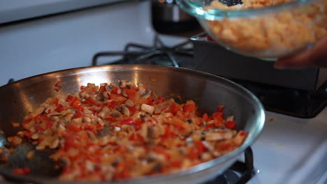 Adding-a-quinoa-and-chickpea-mixture-to-fried-peppers,-onions-and-mushrooms-to-make-a-filling-or-stuffing---slow-motion