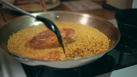 Pan-seared-chicken-breast-simmering-in-a-skillet-of-coucous-and-savory-sauce---slow-motion