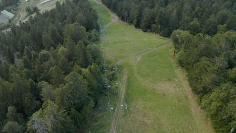Aerial-view-flying-above-wilderness-resort-cable-car-wires-among-wilderness-forest-trees