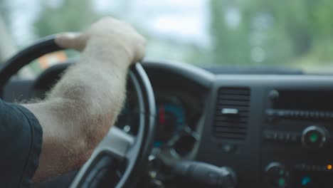Driver's-Hand-On-The-Steering-Wheel-While-Driving-A-Car-On-The-Road---extreme-close-up