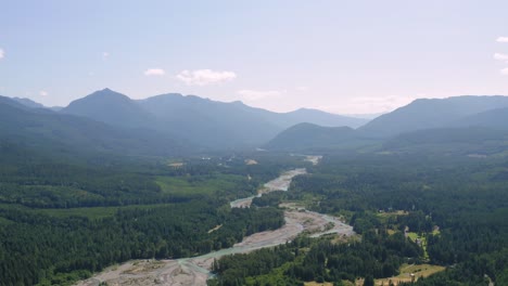 Astounding-Aerial-View-Of-The-Cowlitz-River-Surrounded-By-Lush-Trees-In-Washington-State-With-Misty-Valley-In-The-Background---ascending-drone-shot