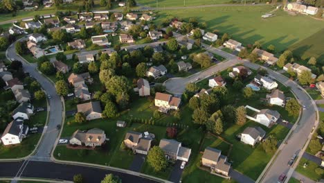 High-aerial-of-neighborhood-community-residential-housing-development,-homes-along-quiet-winding-streets-in-United-States-of-America-USA