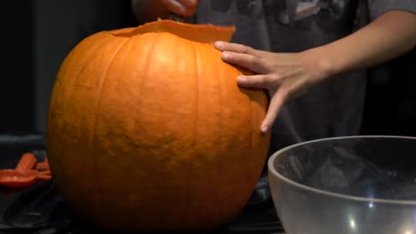 Small-hands-pulling-off-the-top-of-a-carved-pumpkin