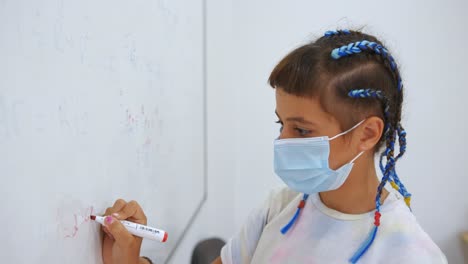 Young-Girl-Student-Wearing-Face-Mask-Answering-Math-Questions-On-White-Board-With-Red-Marker