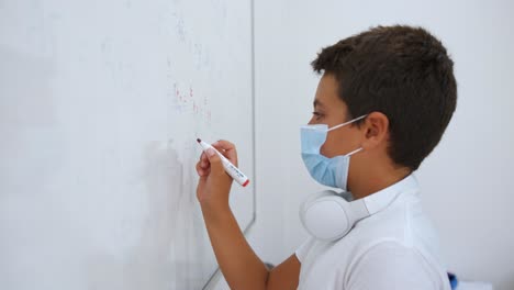 School-Boy-Wearing-Face-Mask-Answering-Math-Questions-On-White-Board-With-Red-Marker