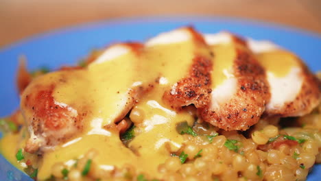 Macro-pull-back-view-of-maple-Dijon-chicken-breast-on-a-bed-of-couscous-covered-in-thick,-rich-gravy
