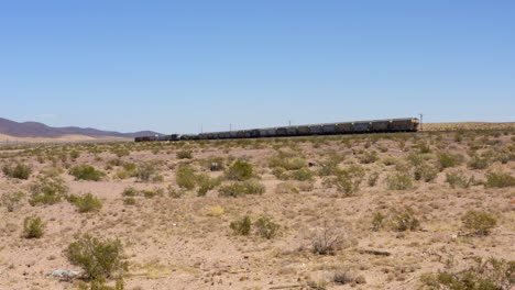 Short-freight-train-shipping-goods-speeds-down-straight-train-tracks-in-the-desert
