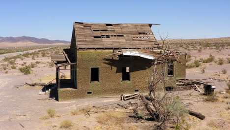 Abandoned-decrepit-run-down-house-sits-alone-in-dry-desert-area-in-midday