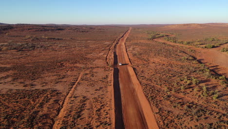 Aerial:-Drone-shot-following-a-vehicle-at-height-but-moves-closer-to-the-vehicle-as-it-drives-further-along-the-outback-road,-in-Broken-Hill,-Australia