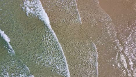 Luftaufnahme-Von-Kleinen-Wellen,-Die-Am-Sandstrand-Brechen