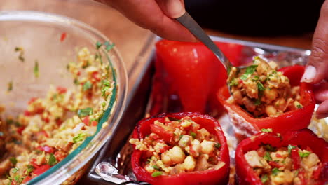 Isolated-view-of-red-bell-peppers-being-filled-with-tasty-chickpea-stuffing---slow-motion