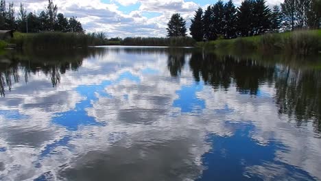 Blauer-Lebendiger-See-Wasserspiegelreflexion-Heller-Szenischer-Bewölkter-Himmel