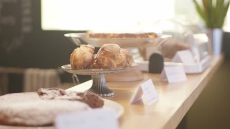 Organic-backing-goods-presented-on-platter-food-stands-on-a-counter-in-a-restaurant-with-cakes-and-muffins-and-a-green-plant