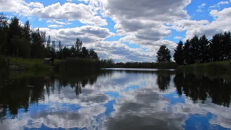 Blue-lake-water-rippling-mirror-reflection-bright-scenic-cloudy-sky