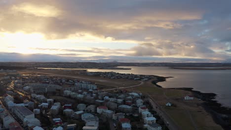 Aerial-above-a-small-village-along-coastline-in-Iceland-during-dreamy-sunset