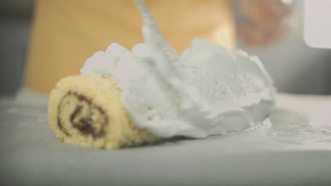 Close-up-of-egg-white-cream-put-on-a-delicious-swiss-roll-with-a-knife-by-a-vegan-chef